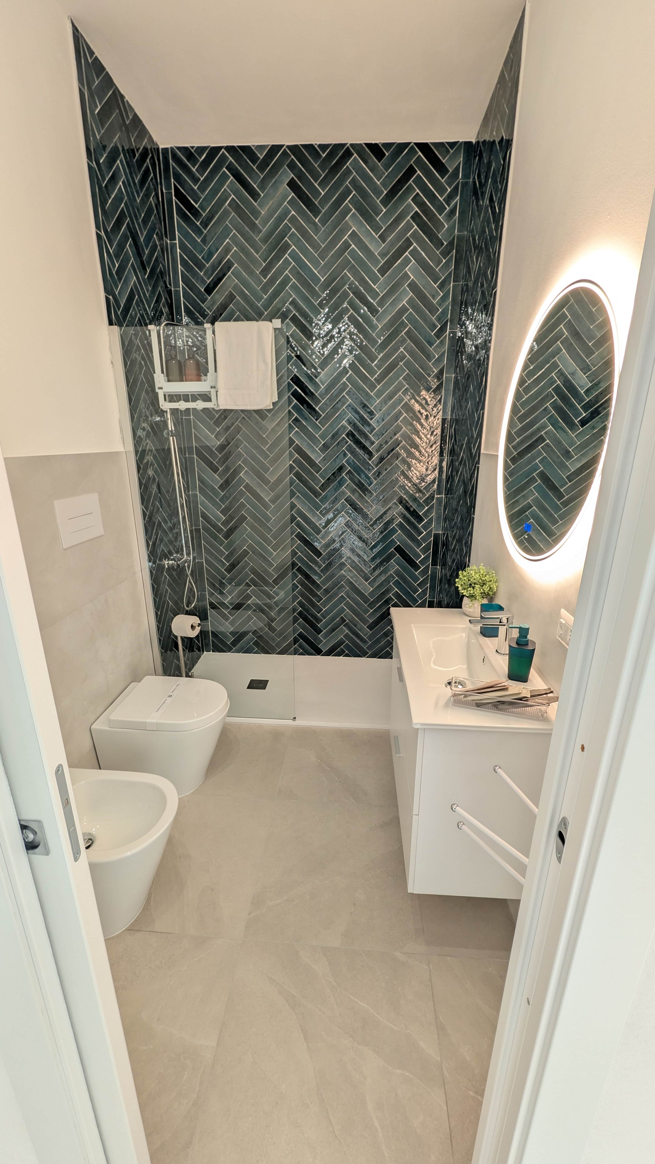 Un bagno moderno con rivestimento a mosaico a spina di pesce, una vasca freestanding, un water, un bidet e un mobile lavabo con specchio e lavandino.
