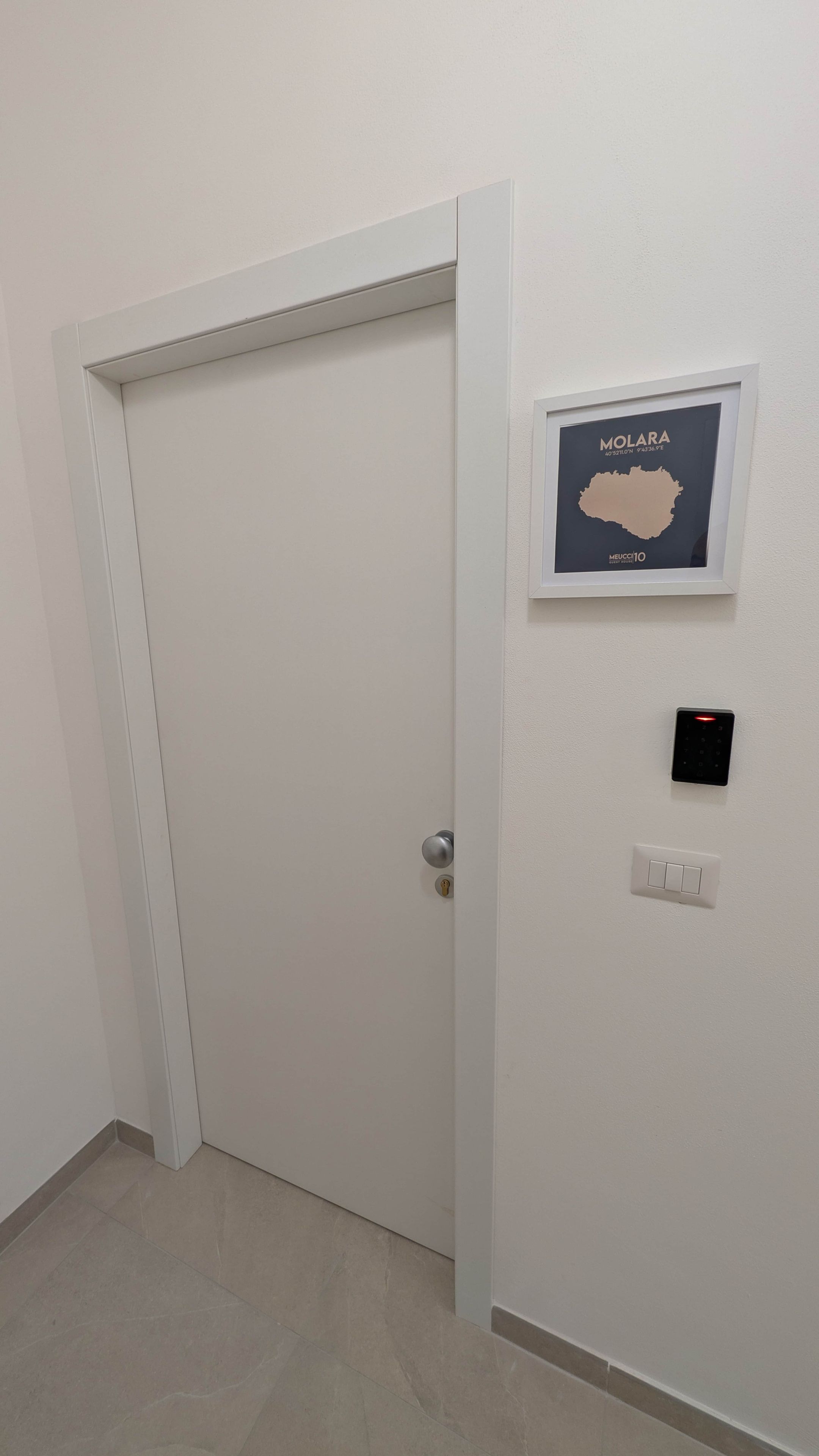 Eine geschlossene Tür mit einem Schlüsselfeld und einer Karte von Molara im Rahmen an der Wand.