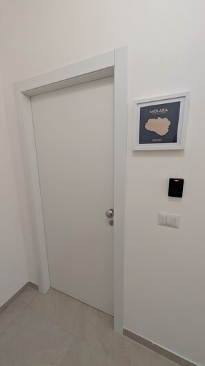 A closed door with a keypad lock and a framed map of Molara on the wall. - Molara - Comfort Double Room (Olbia)