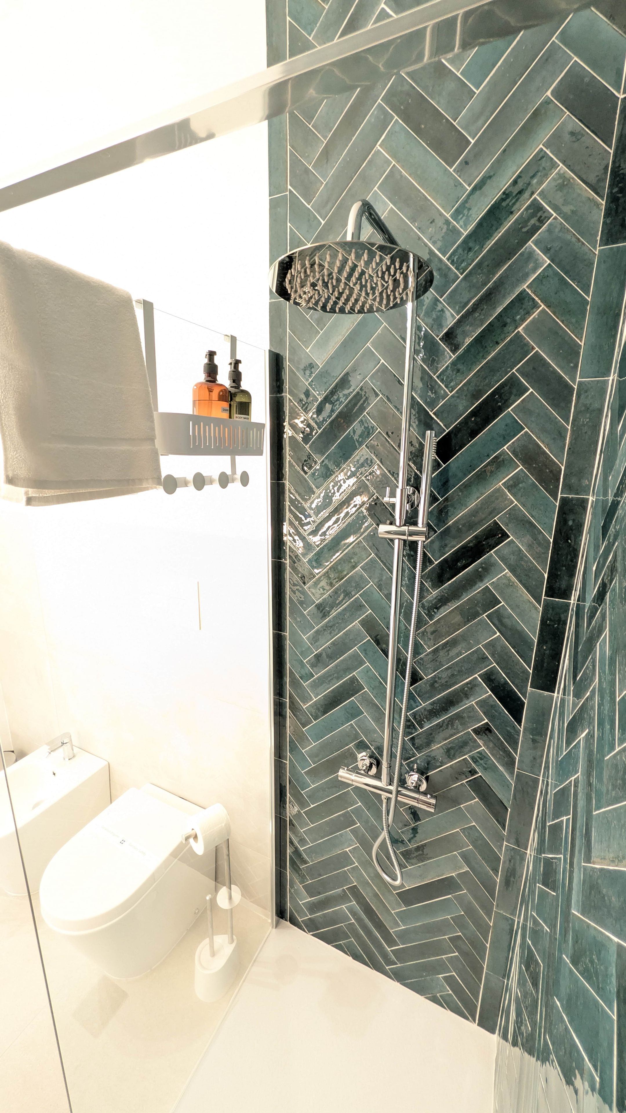 A modern bathroom with a glass-enclosed shower, a white sink, and a towel rack.