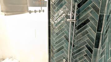 A modern bathroom with a glass-enclosed shower, a white sink, and a towel rack.
