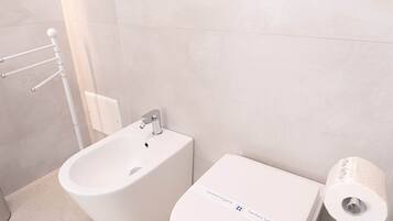 Un baño moderno con un bidé, inodoro y un secador de manos.
