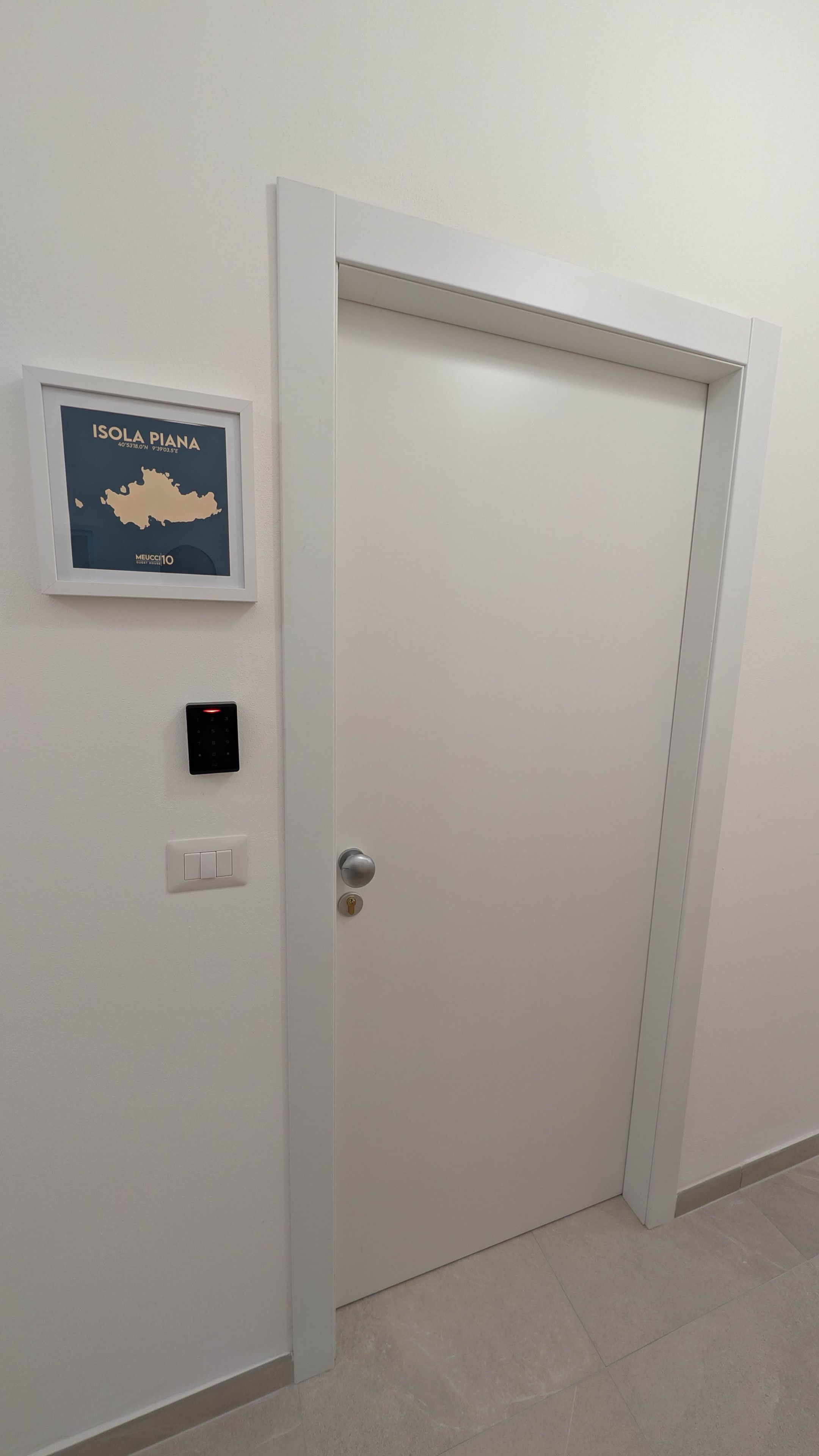 Eine geschlossene Tür mit einem Schlüsselfeld und einem Lichtschalter an der Wand.