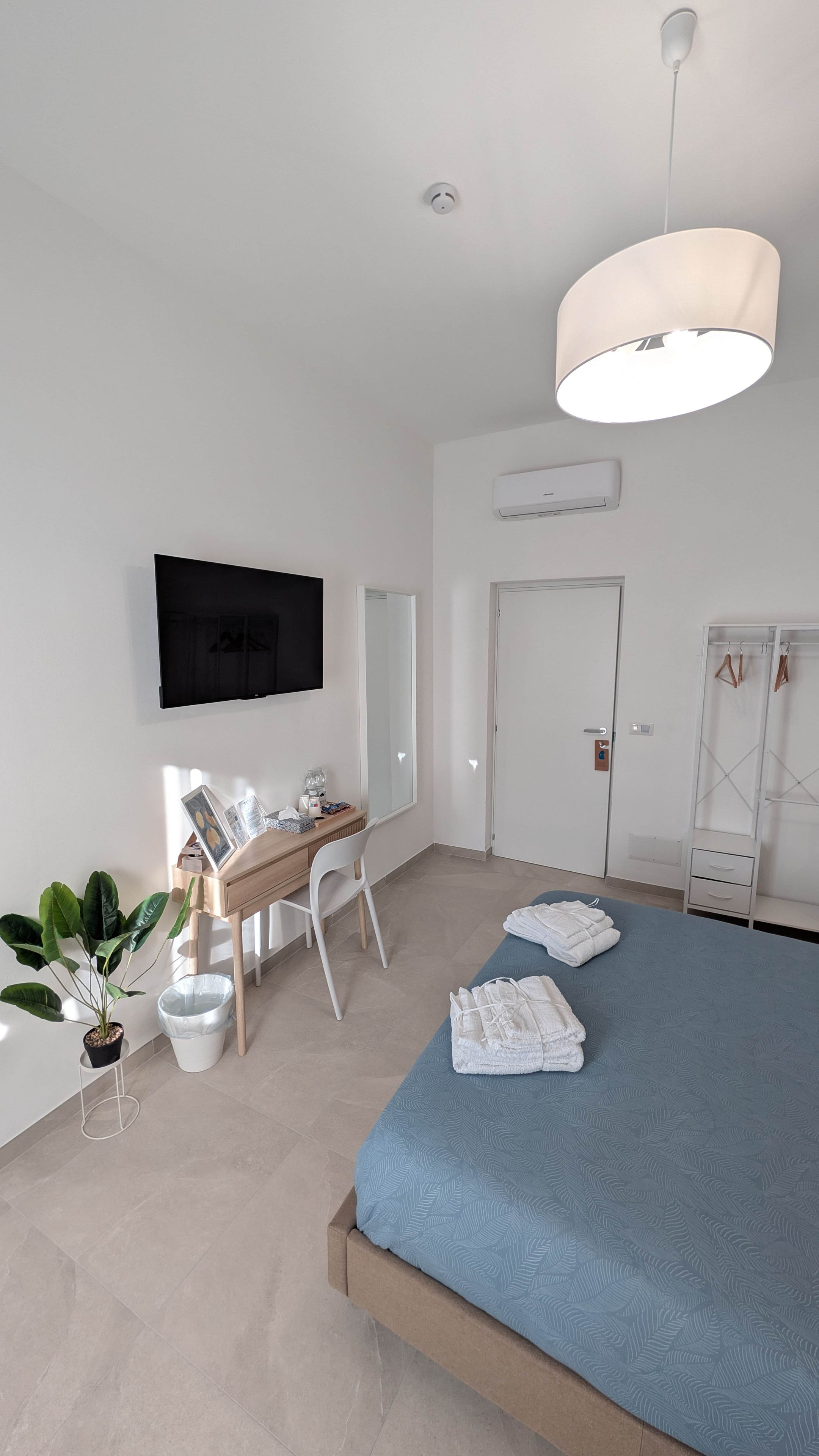 Ein modernes Schlafzimmer mit einem Bett, einem Schreibtisch, einem Stuhl, einem Fernseher und einem Kleiderschrank.