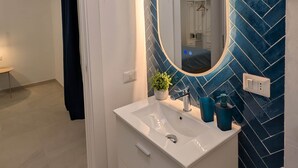 Un baño con tocador blanco, espejo con luz y salpicadero de azulejos tipo espiga azul.