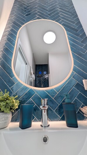 Ein Badezimmer mit modernem Design, ausgestattet mit einem großen Spiegel, einem Waschbecken und einer Topfpflanze.
