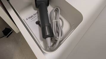 A white bathroom sink with a hair dryer and its cord.
