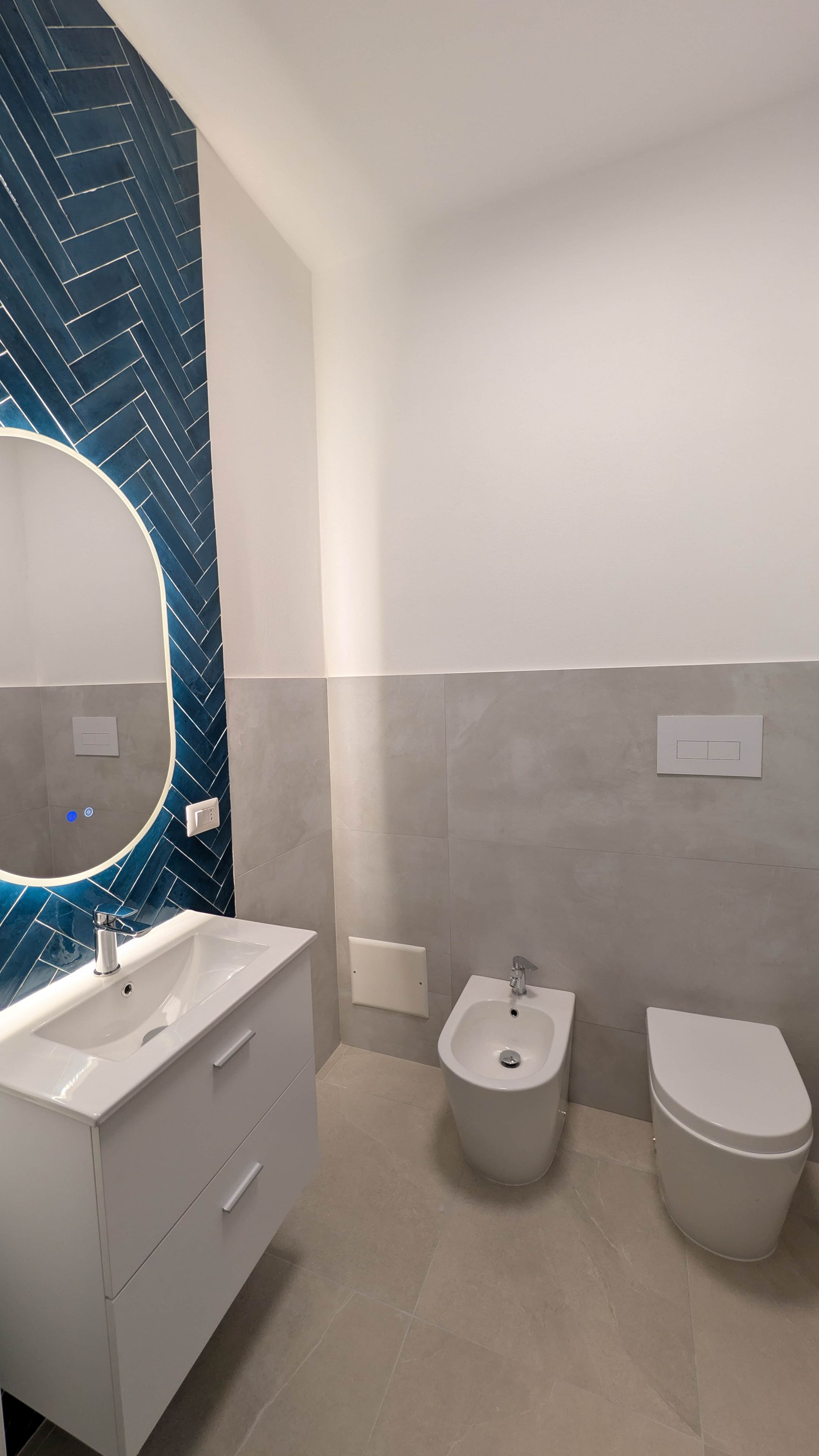 Ein modernes Badezimmer mit einem weißen Waschtisch, einem Bidet und einer Toilette.