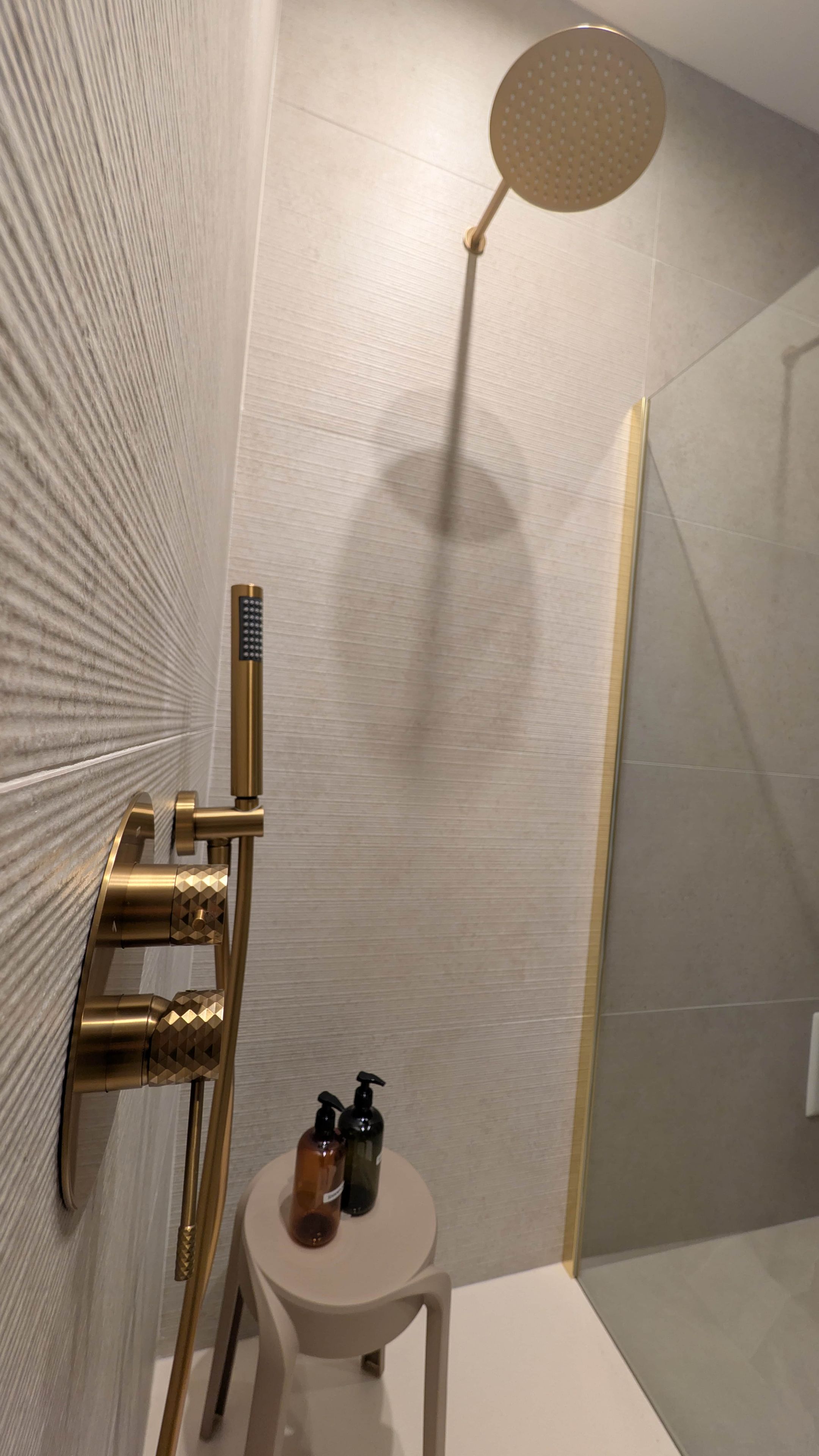 Ein Badezimmer mit Dusche, Handtuchhalter und einem kleinen Tisch mit Toilettenartikeln.