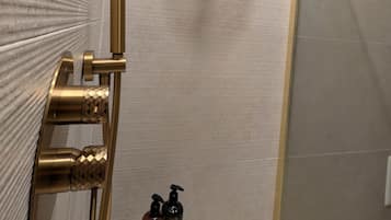 Ein Badezimmer mit Dusche, Handtuchhalter und einem kleinen Tisch mit Toilettenartikeln.