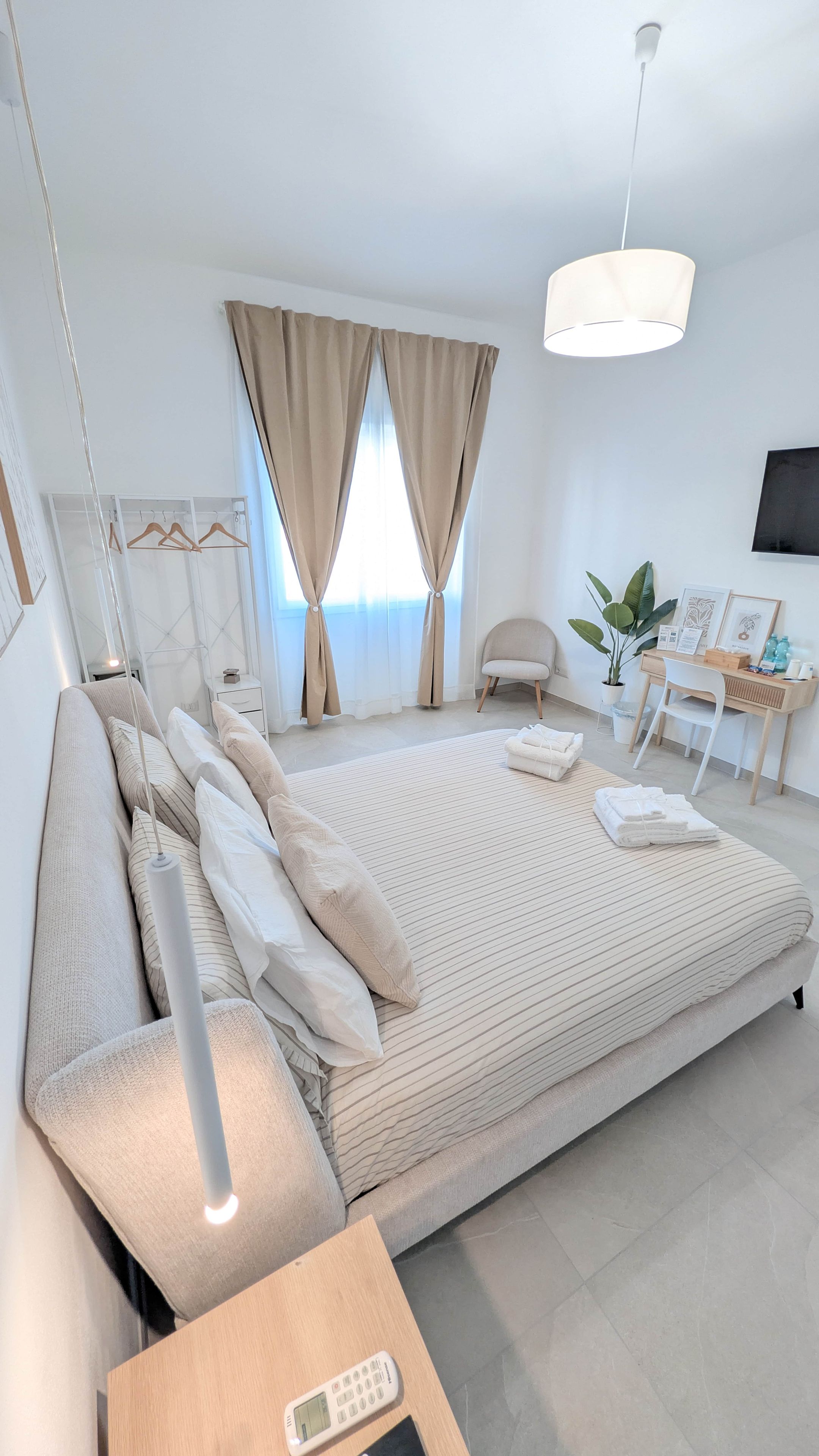 A modern bedroom with a large bed, bedside tables, a desk, and a chair.