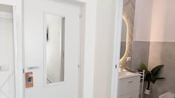 A modern bathroom with a white sink, a mirror, and a toilet.