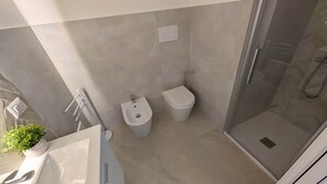 Une salle de bain moderne équipée d’une douche, de toilettes, d’un bidet et d’une petite plante en pot.