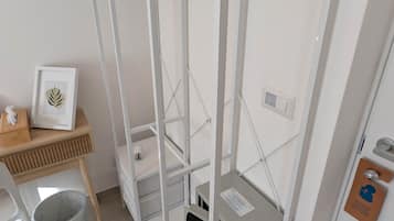 Habitación compacta con armario empotrado, una pequeña mesa con un marco de fotos y un cubo de basura.