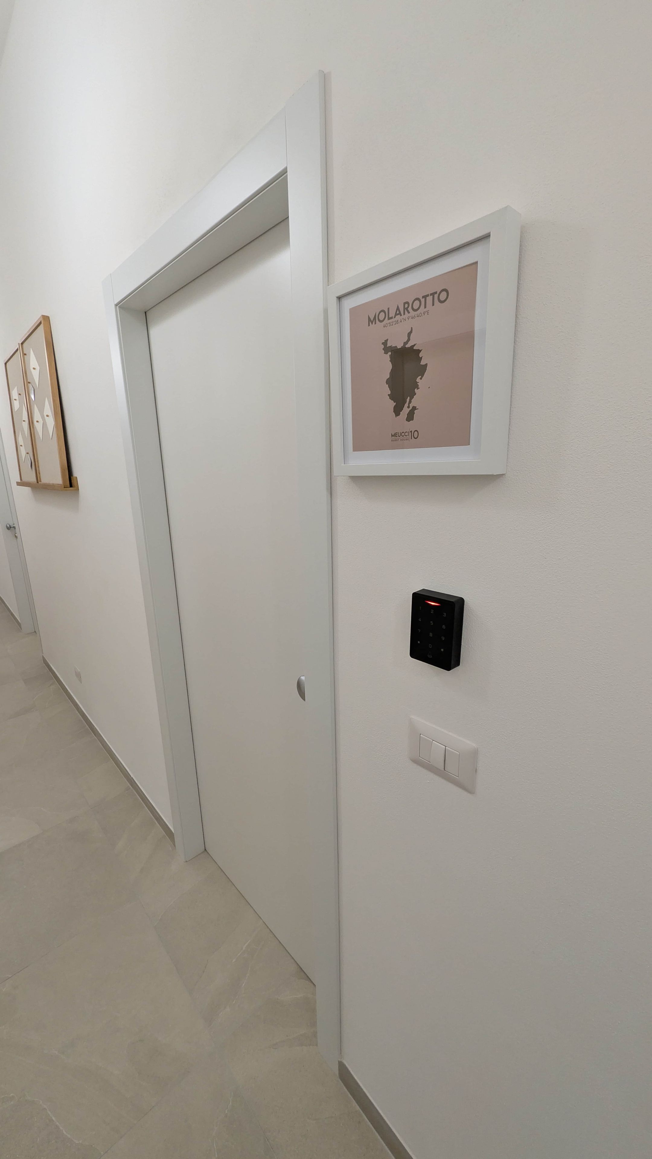 Un corridoio con una mappa incorniciata di Molarotto, una porta e un dispositivo fissato al muro.