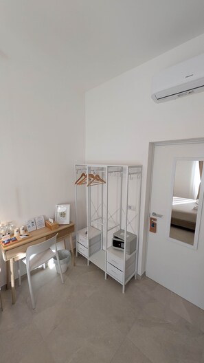 Camera d'albergo con una scrivania in legno, un armadio bianco, un forno a microonde e un letto con vista sull'esterno.