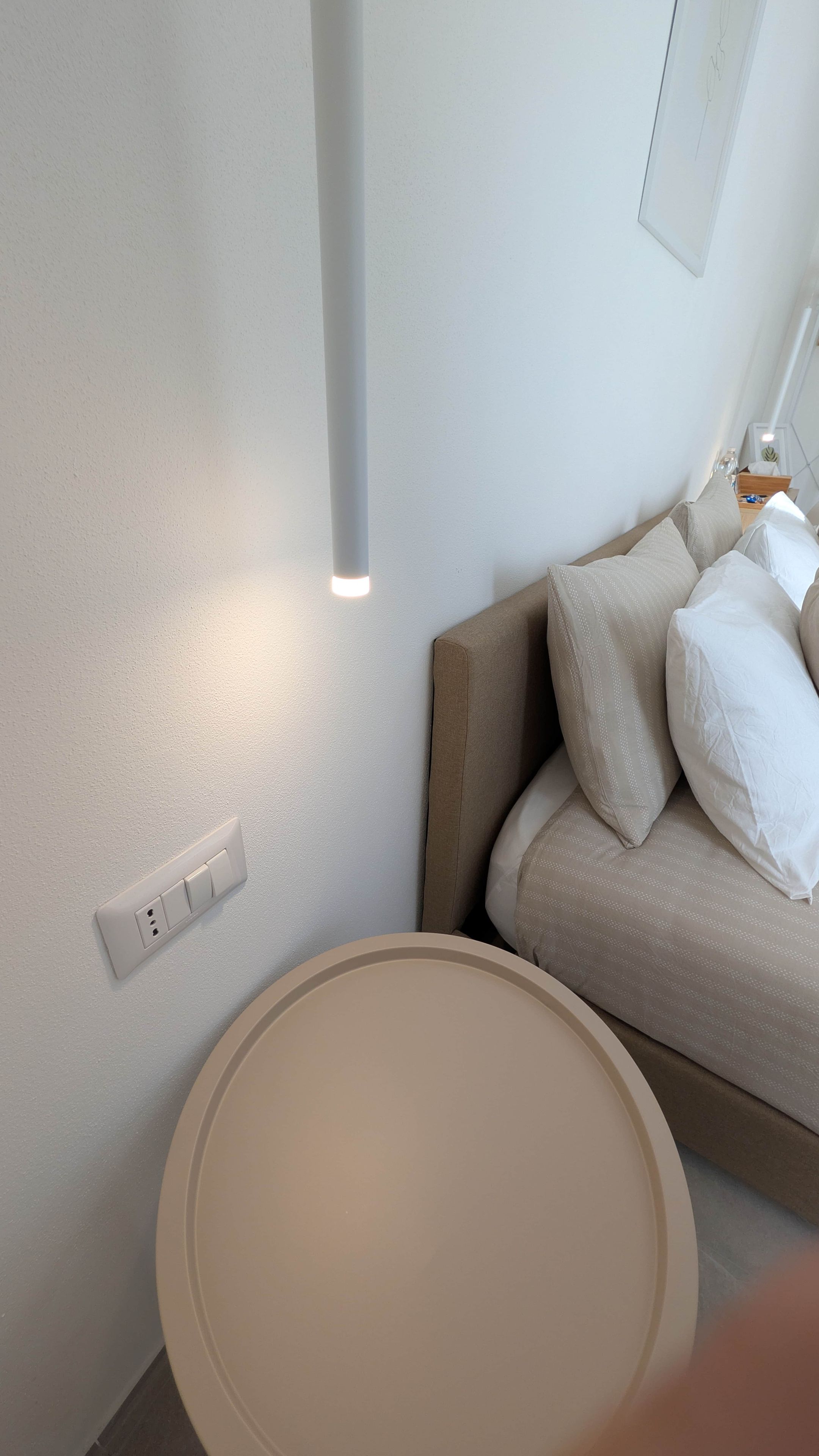 Ein modernes Zimmer mit einem runden Tisch, einer Couch mit Kissen, einer Steckdose und einer Lampenleuchte.