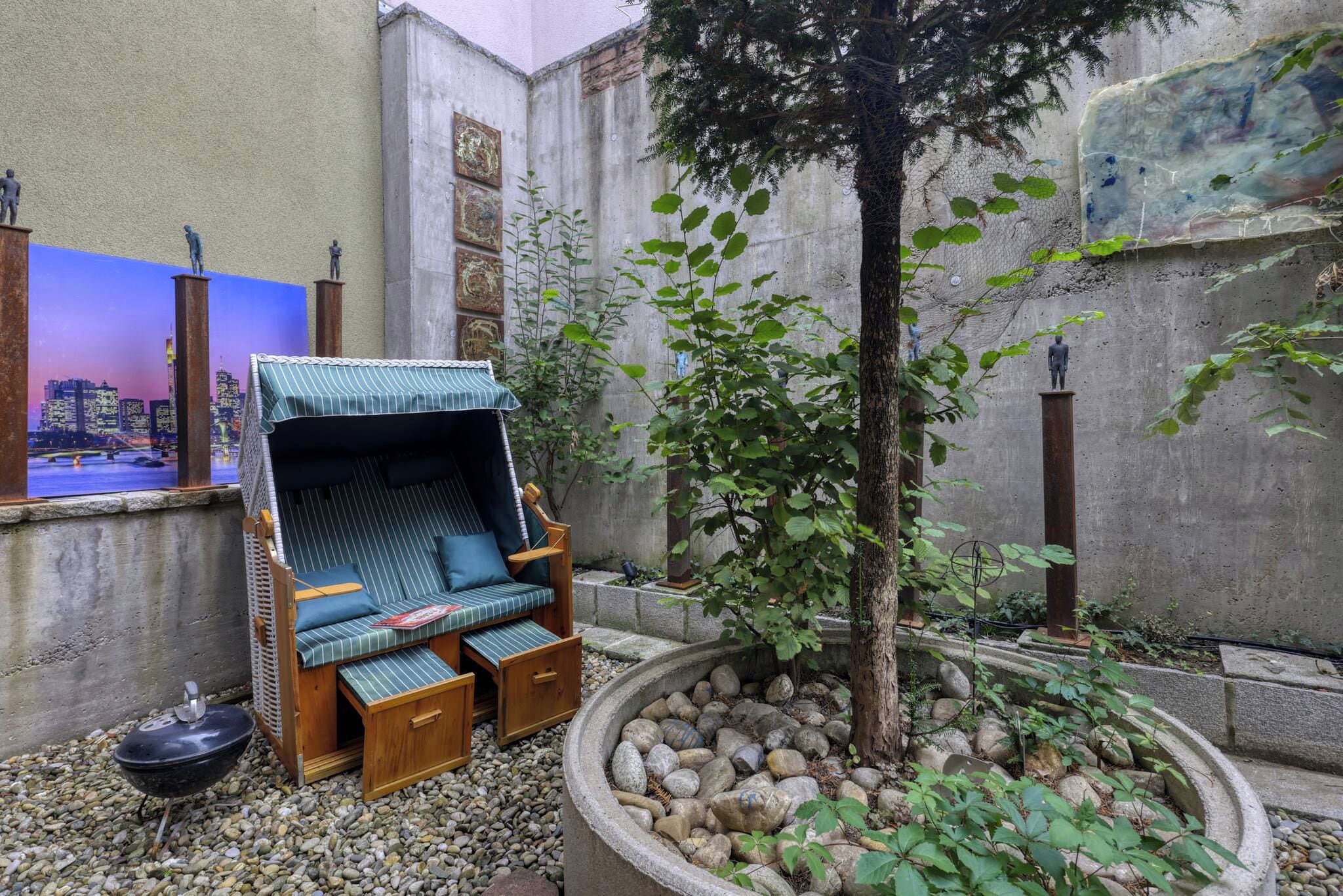 Un petit espace extérieur aménagé avec un banc rembourré et un arbre.