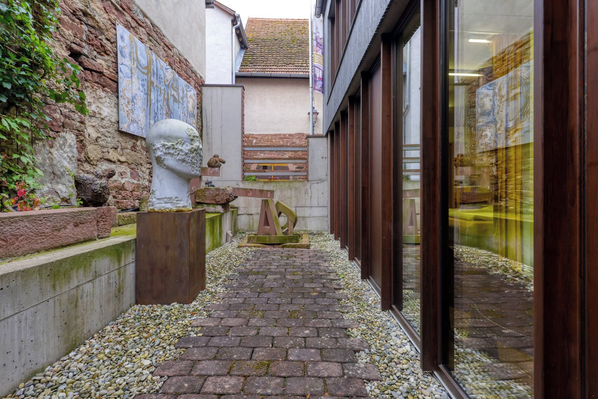 A narrow alleyway with cobblestone flooring, a stone wall on one side, and a building entrance on the other.