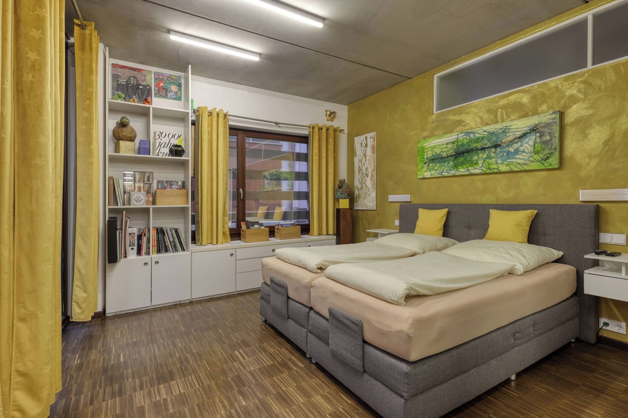 A bedroom with a bed, a wardrobe, a desk, and a window with curtains.