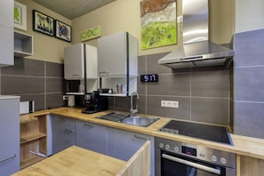 A modern kitchen with a digital clock, stainless steel appliances, and wooden countertops. - Exclusive Suite in Marktheidenfeld - Modern Comfort Meets Original Art (Marktheidenfeld)