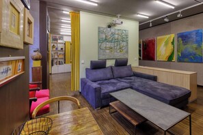 A modern living room with a sectional sofa, a wooden coffee table, and a red chair. - Exclusive Suite in Marktheidenfeld - Modern Comfort Meets Original Art (Marktheidenfeld)