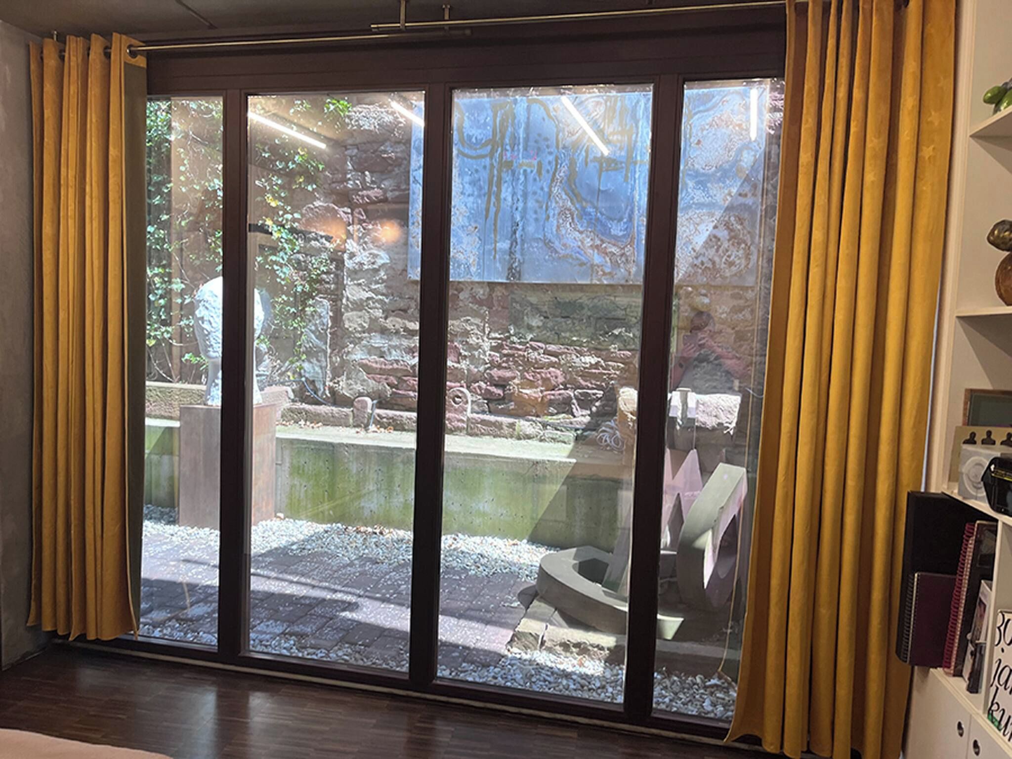 A room with a large sliding glass door leading to an outdoor area with a rock garden and a small pond.