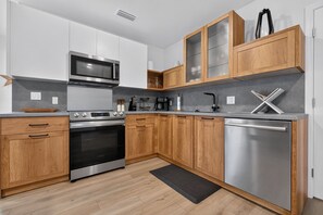 A modern kitchen with stainless steel appliances, wooden cabinets, and a grey countertop. - Charming 2-Bedroom Home Near Siesta Key, Sleeps 6 (Sarasota)