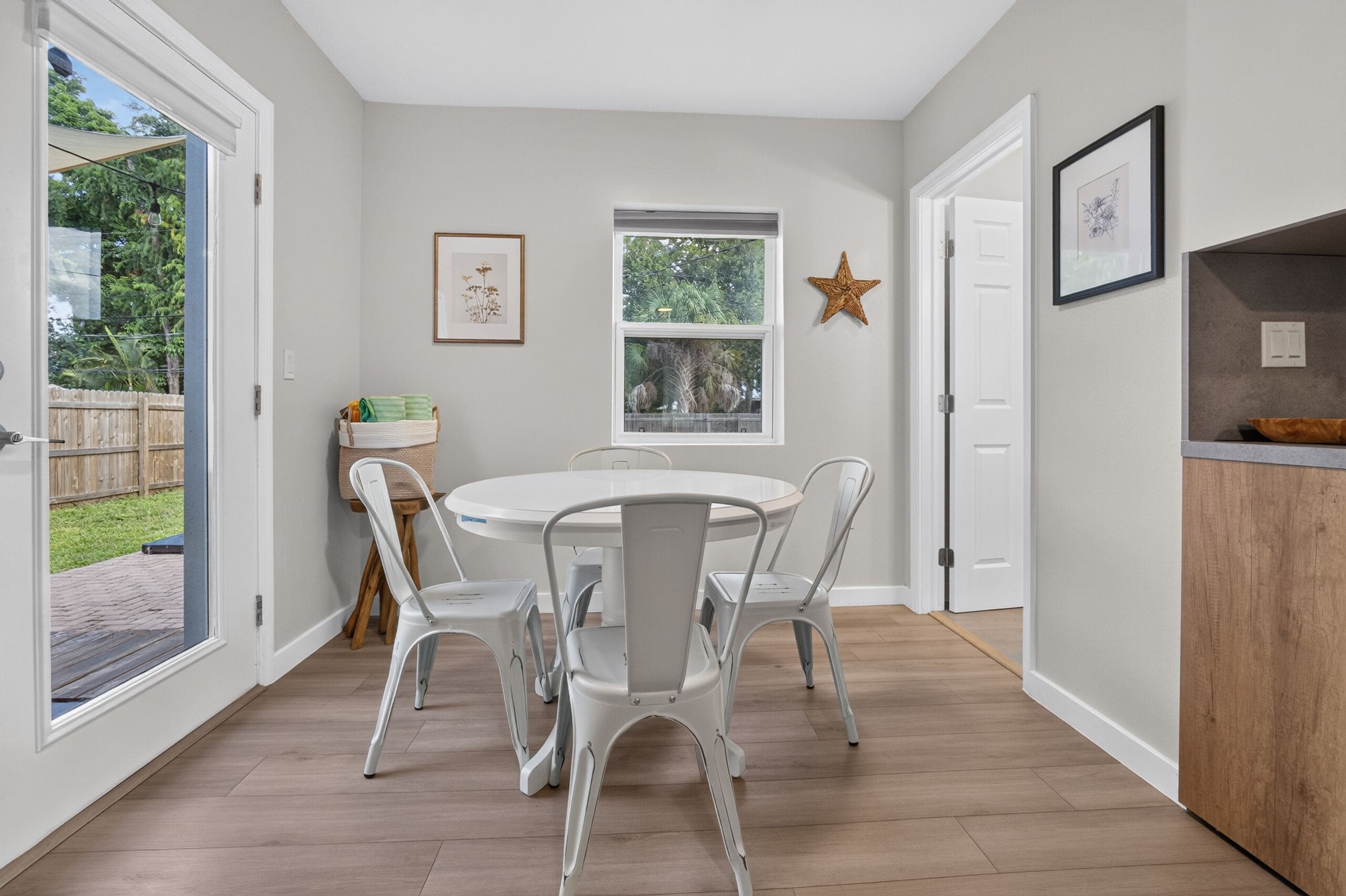 Une pièce avec une table ronde, quatre chaises, une fenêtre et une porte.