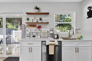 A modern kitchen with white cabinets, a coffee bar, and a window with a view of greenery. - 3-bedroom house in beautiful St. Cloud with cool AC breeze (St. Cloud)