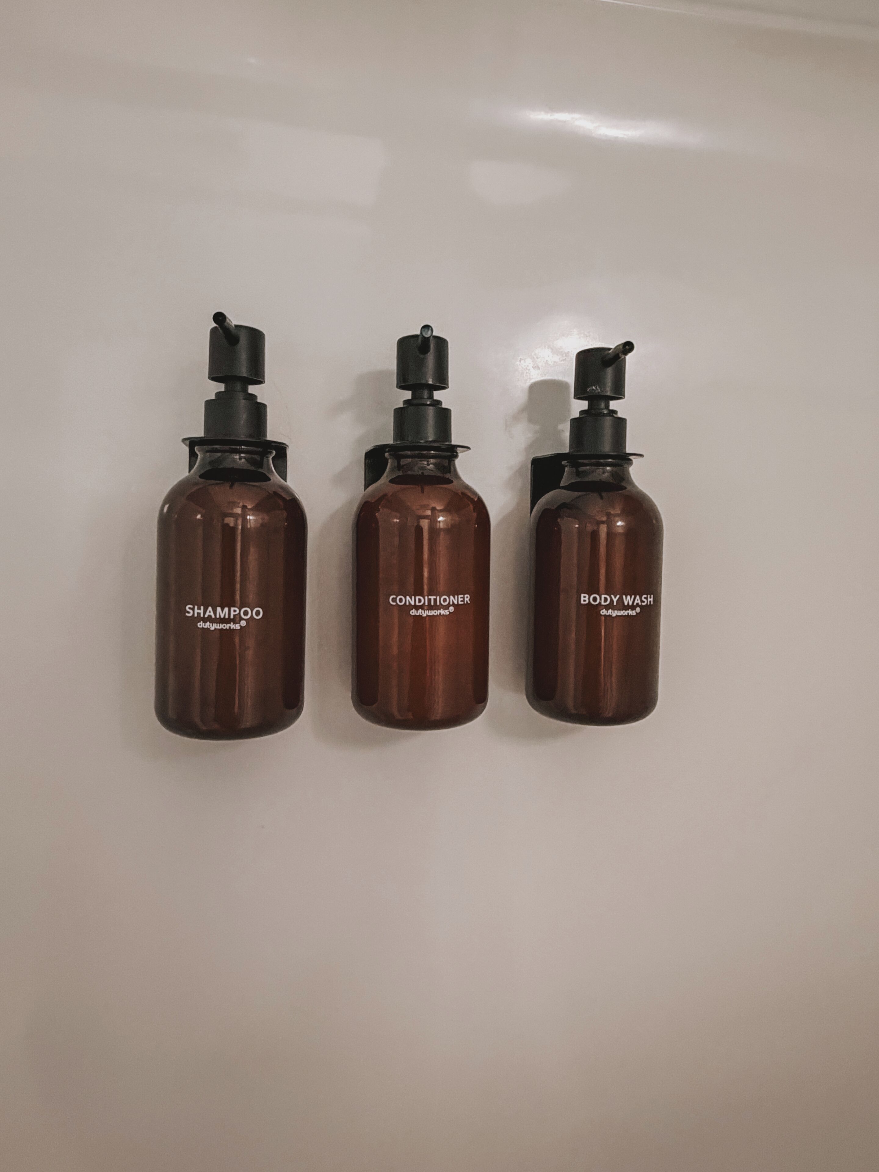 Three bottles of toiletries on a white surface.