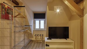 A small room with a TV on a stand, a metal shelf unit, and a wooden bench. - Maisonette Apartment The Haystack Ad1716 (Marktheidenfeld)