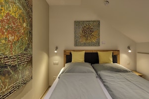 Un dormitorio con una cama, dos lámparas de noche, una obra de arte en la pared y una lámpara de techo.