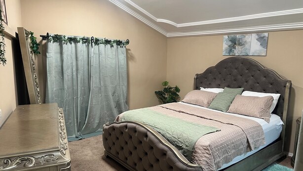 A bedroom with a tufted headboard bed, a nightstand, a dresser, a ceiling fan, and a window with curtains. - Luxury loft at 63rd on Oxford Street (Accra)