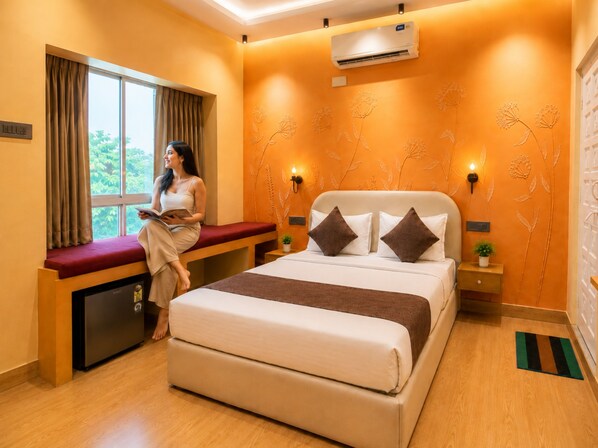 A hotel room with a bed, a bench, a window, and an air conditioning unit.