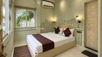 A bedroom with a bed, a window, an air conditioning unit, and a door.