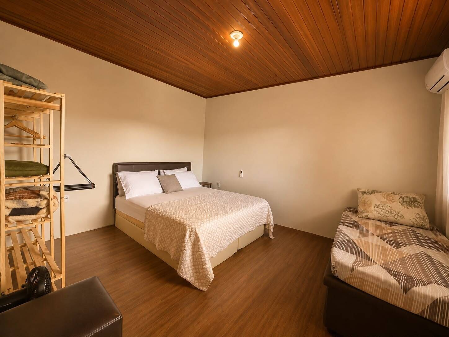 Um quarto com uma cama, um guarda-roupa de madeira e uma mesinha.