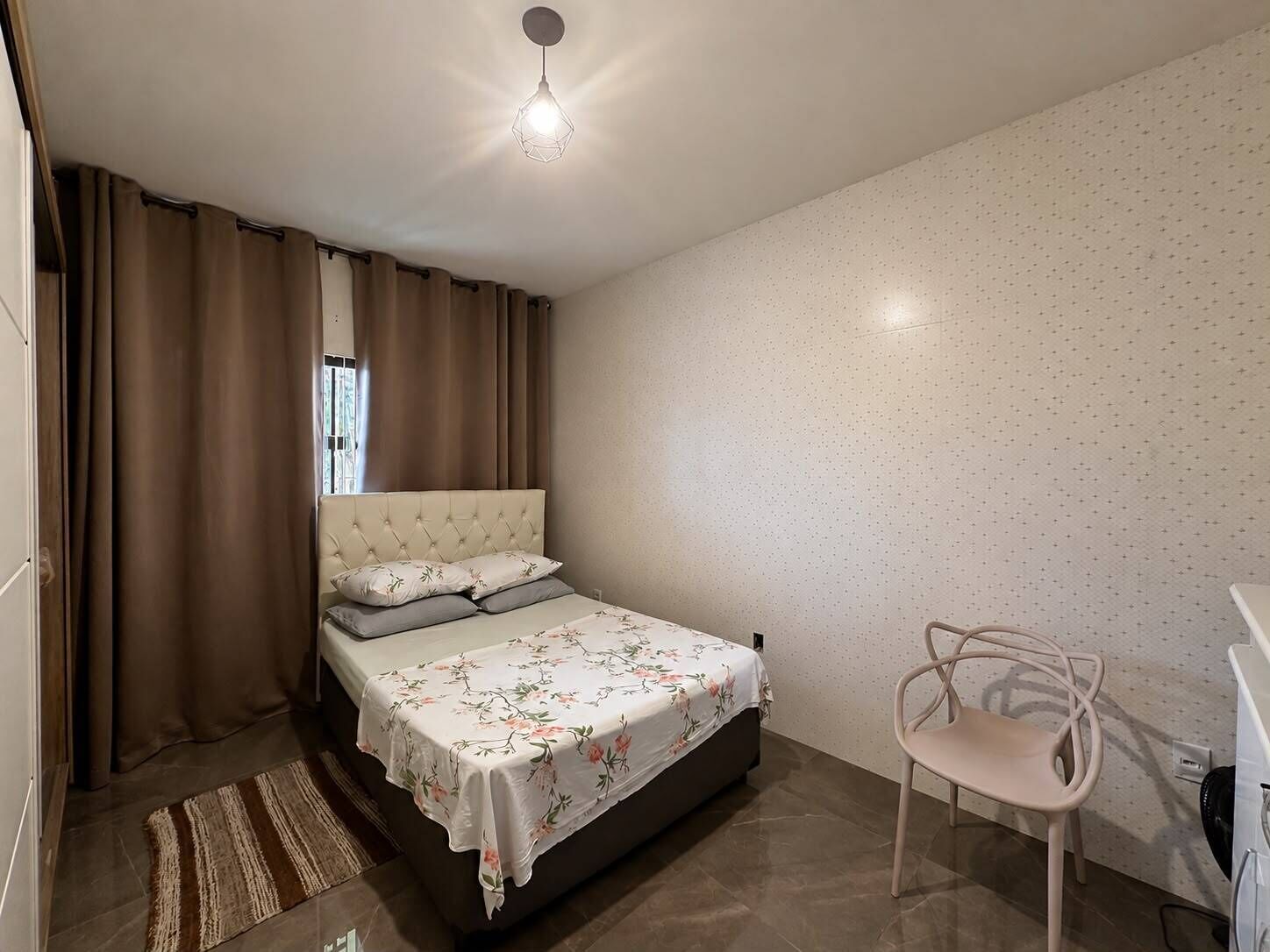 A bedroom with a bed, a chair, and a washing machine.