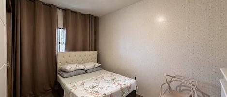 A bedroom with a bed, a chair, and a washing machine.