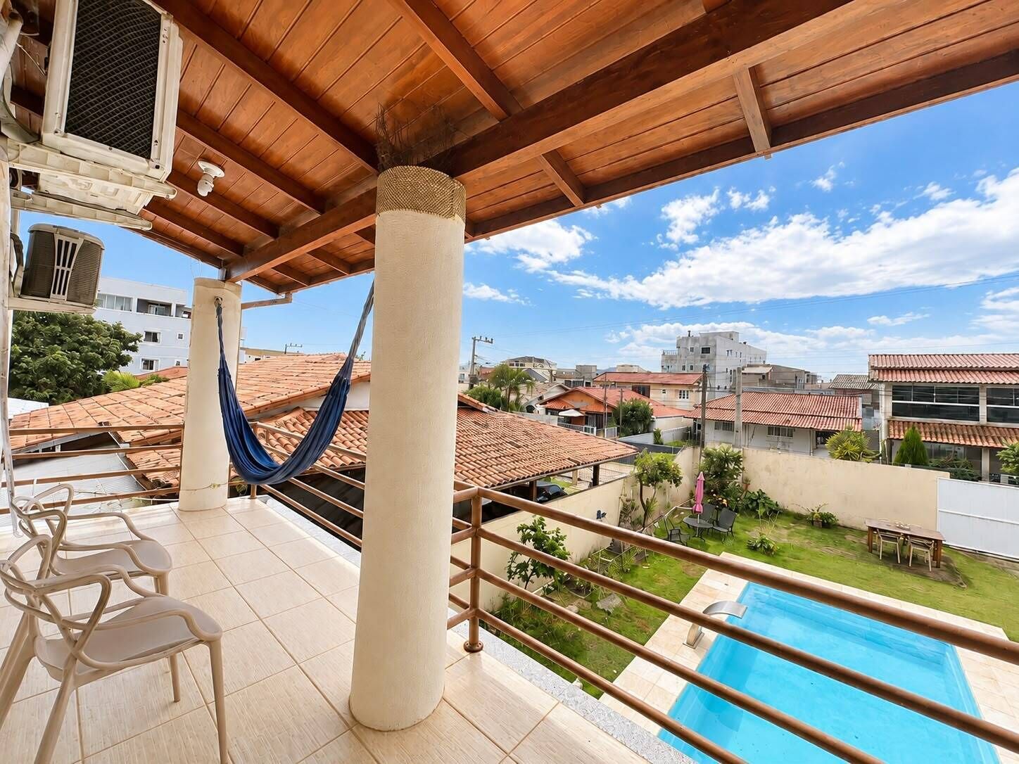 A balcony with a pool, chairs, and a hammock.