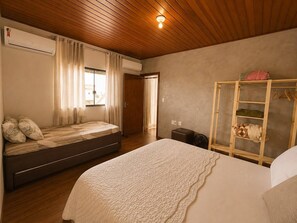Ein Schlafzimmer mit Bett, Kleiderschrank, Klimaanlage und einem fenster mit Vorhängen.