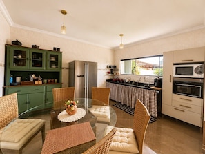Una cocina moderna con una mesa de vidrio, sillas de mimbre, un refrigerador y un microondas.
