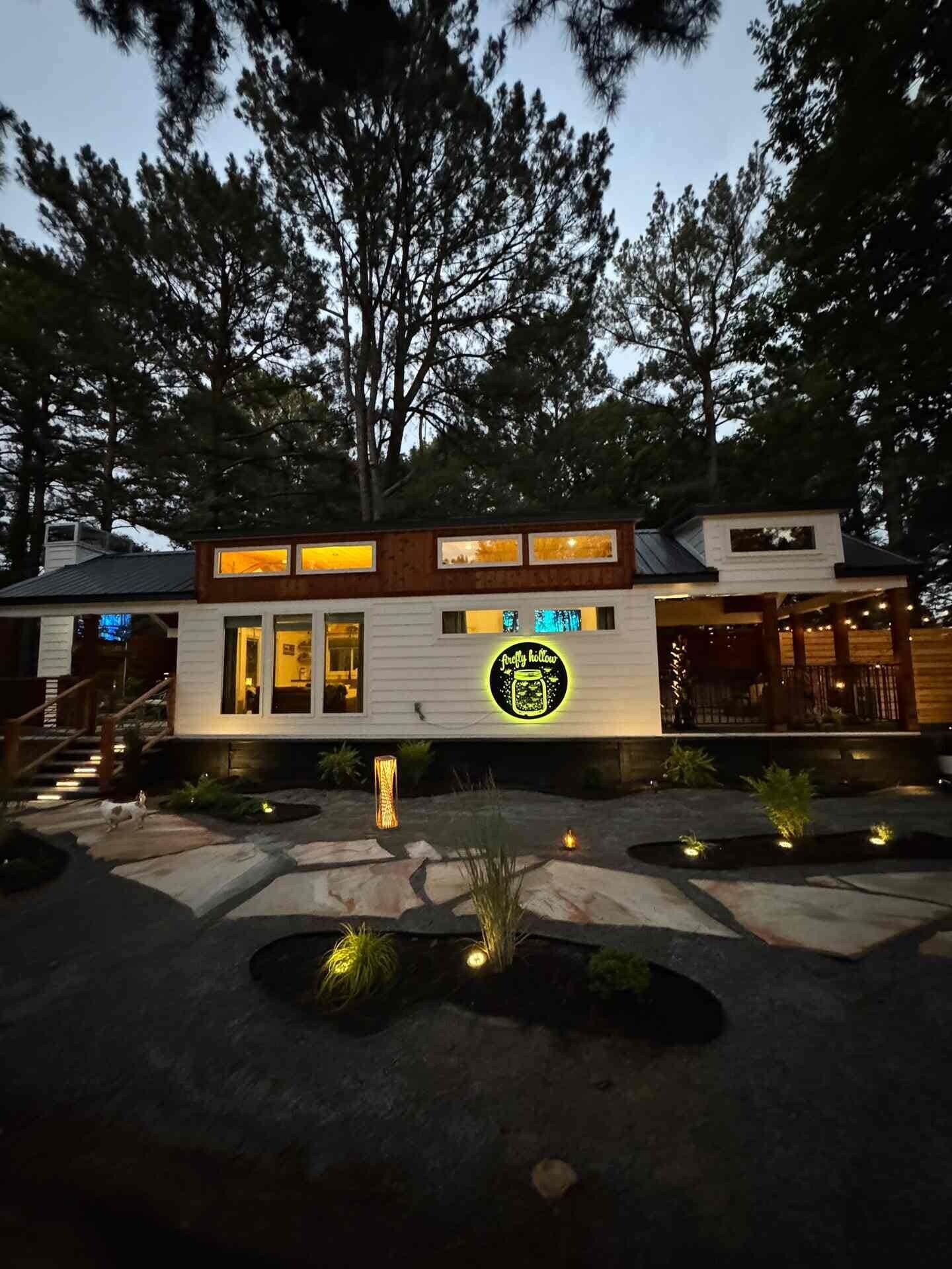 A modern building with a neon sign, a porch area, and a stone pathway.