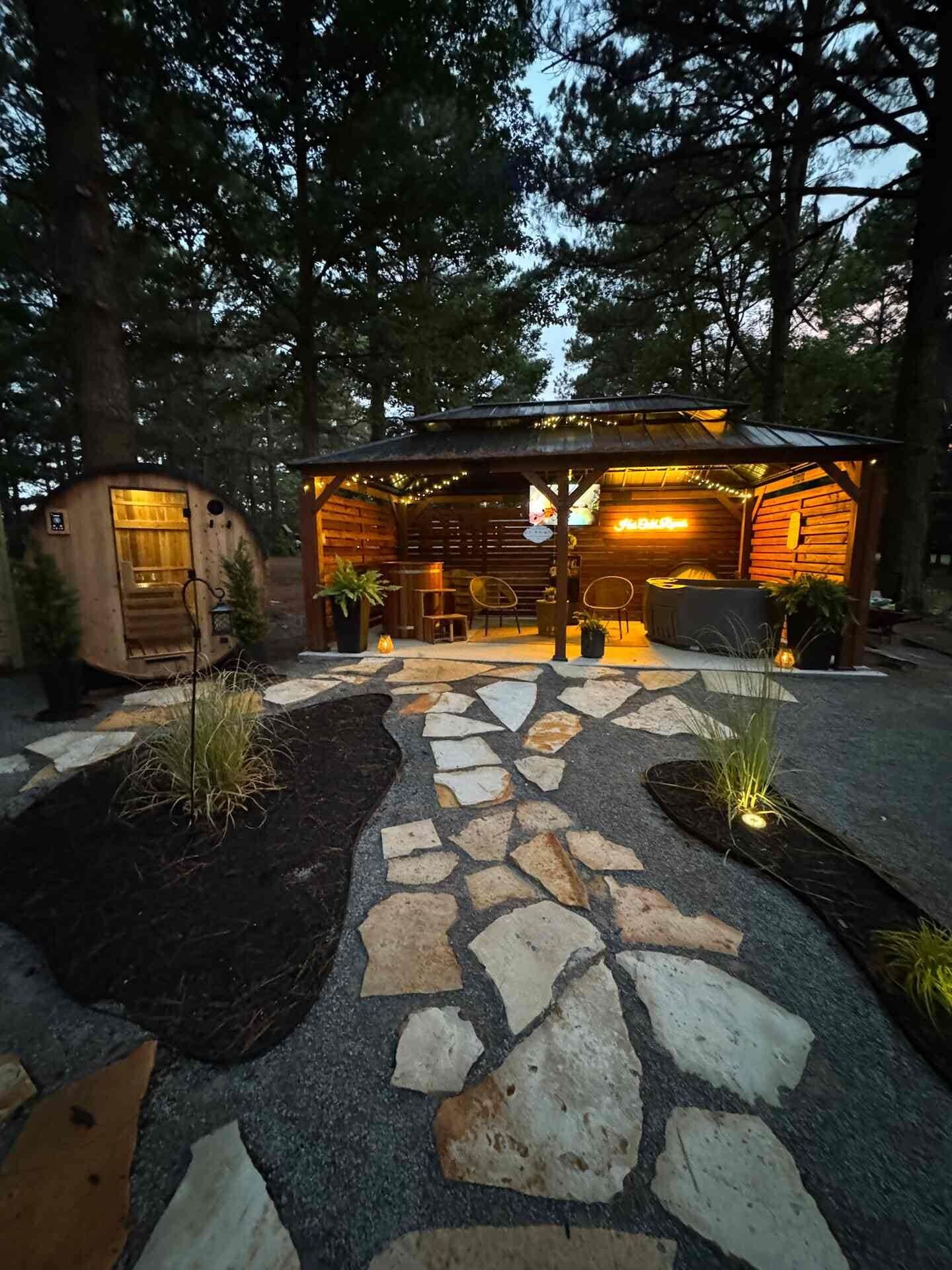 A rustic cabin with a stone pathway leading to a wooden deck and a covered seating area.