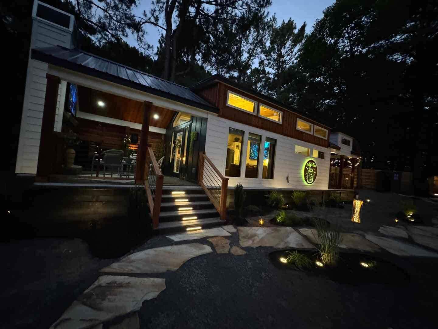 A two-story house with a covered porch, a stone pathway, and a small pond.