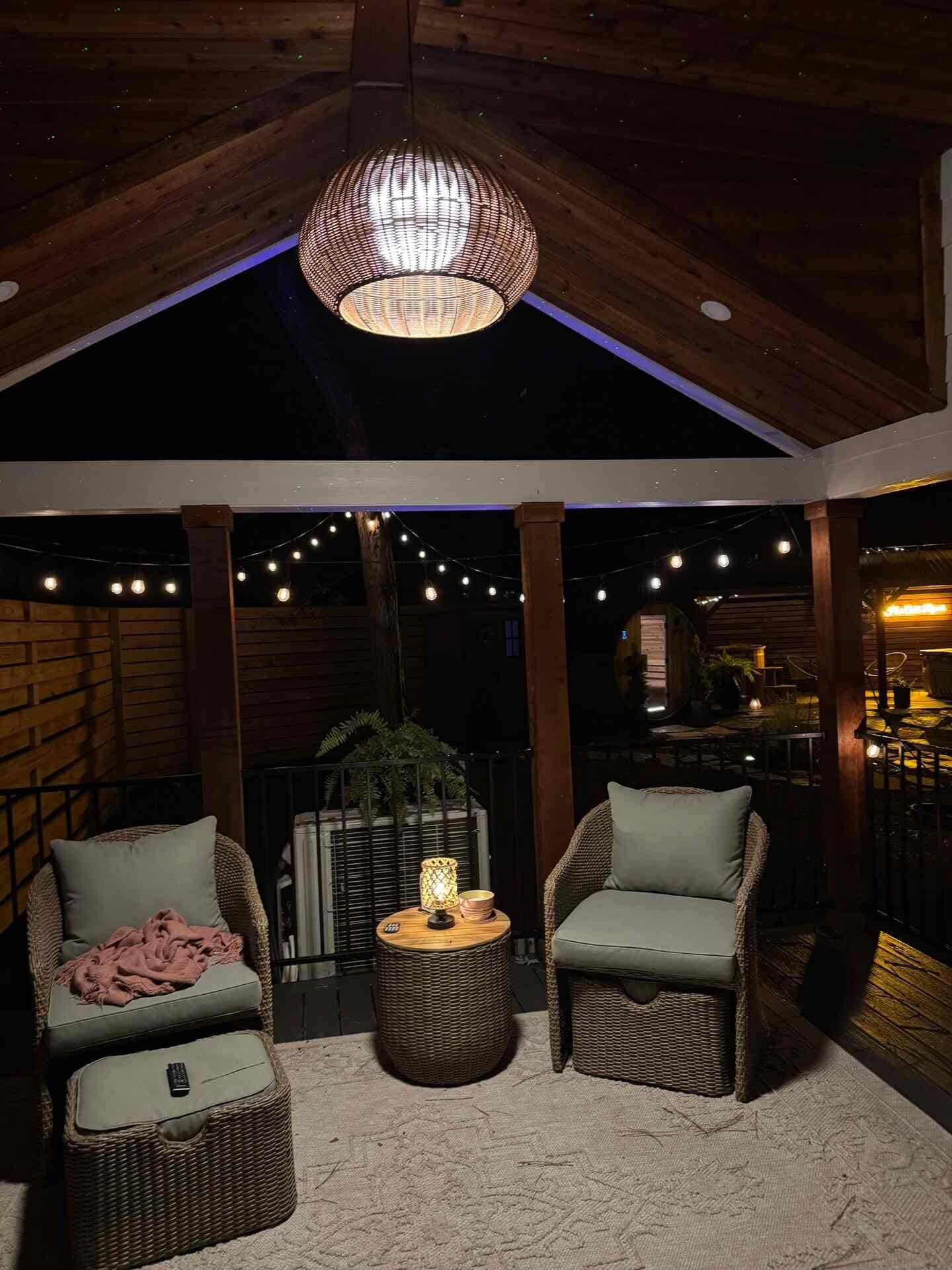 An outdoor seating area with wicker chairs, a round table, and string lights.