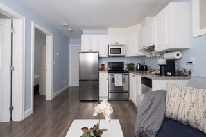 A modern kitchen with white cabinets, stainless steel appliances, and a grey countertop.