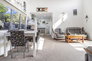 Un interior moderno con comedor, dos sofás y una cocina al fondo.