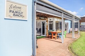 Un'area esterna riparata con tavolo e sedie, un cartello di benvenuto per la famiglia e vista sul giardino.