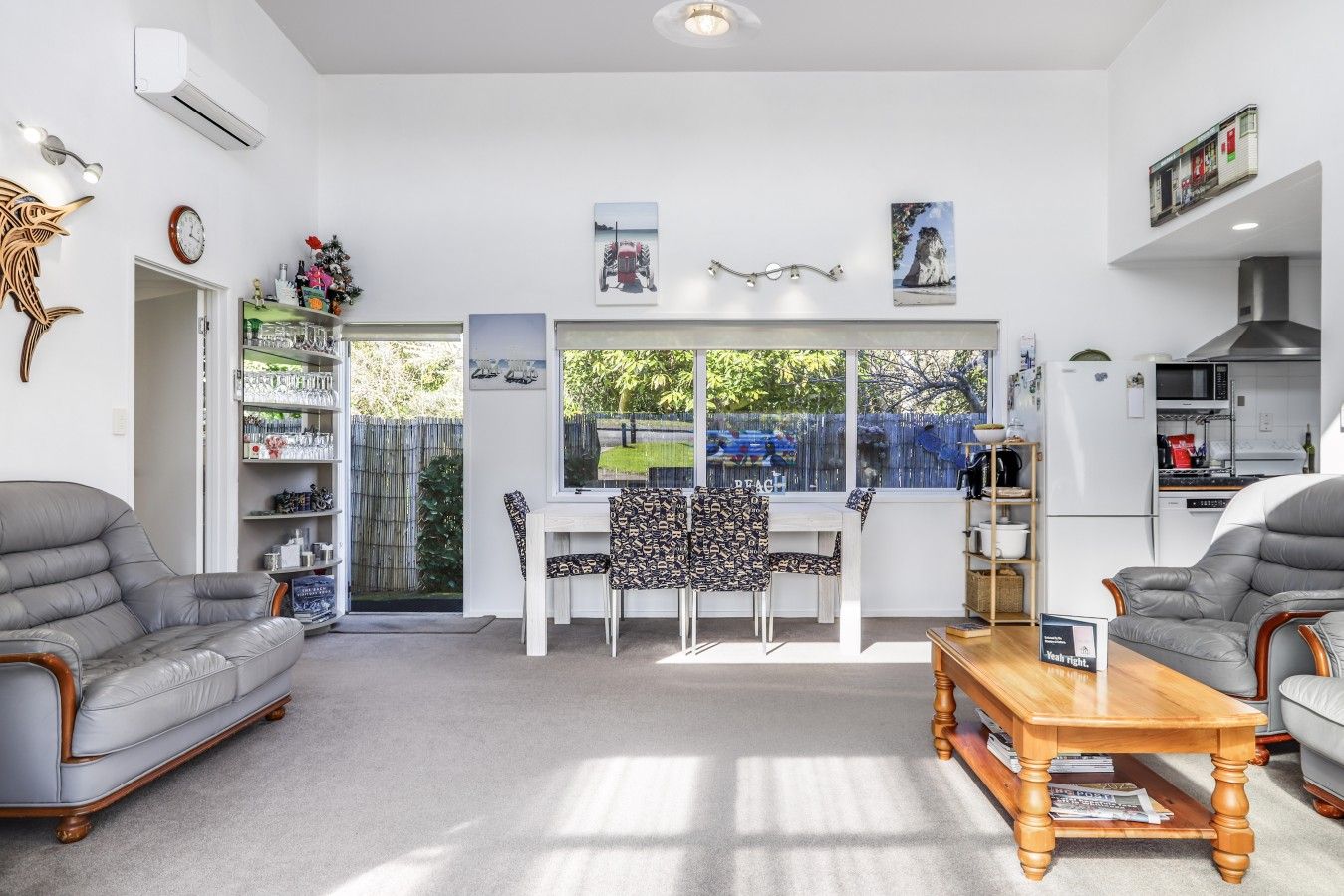 Een moderne woonkamer met een eethoek, een keuken en een groot raam met uitzicht op de omgeving.